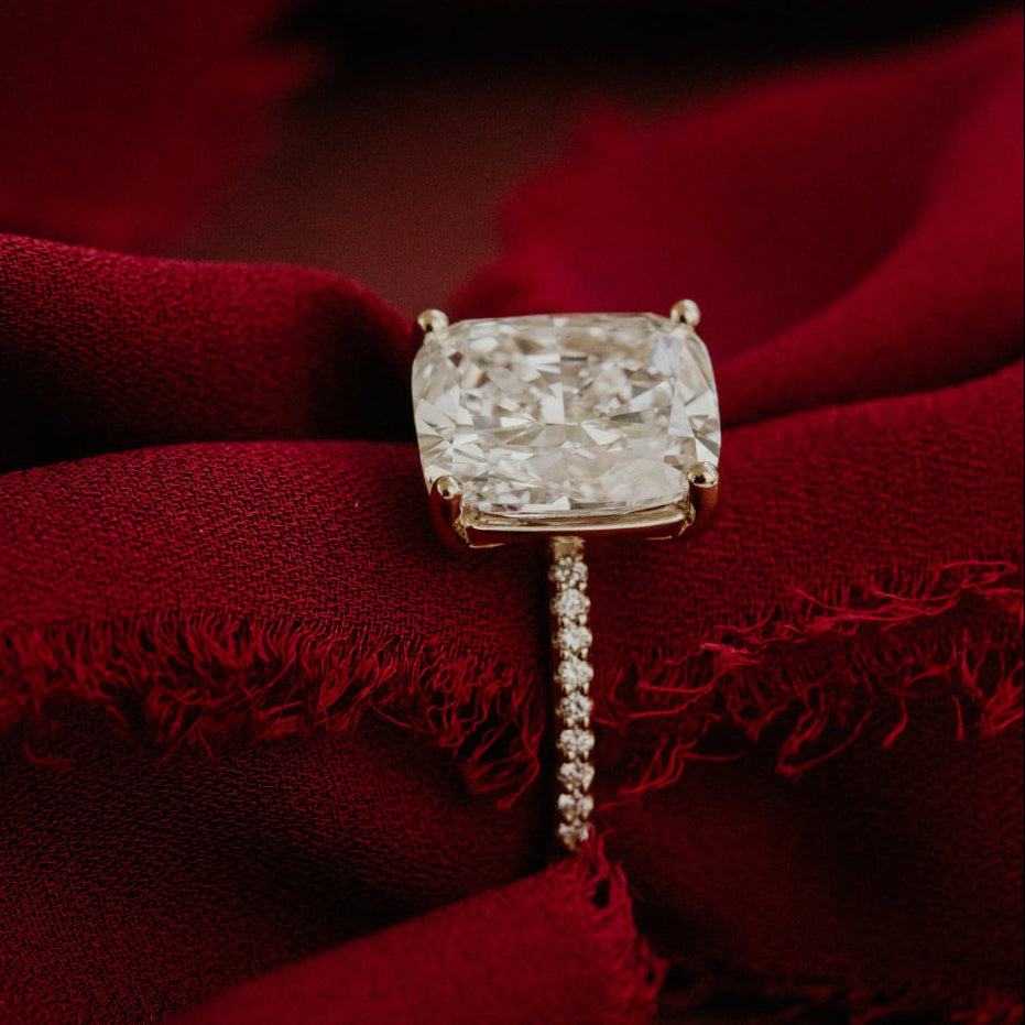 Elongated cushion  diamond ring with a red fabric background