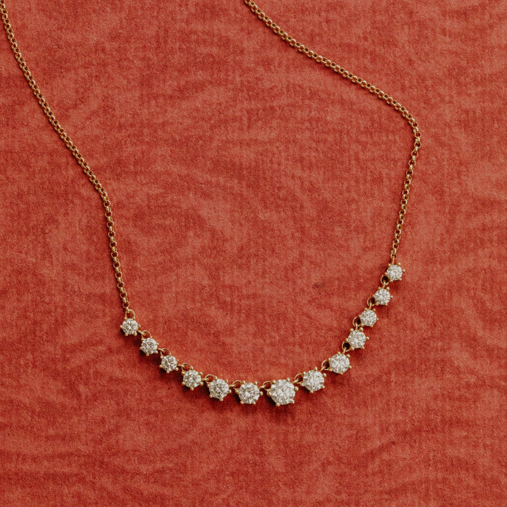 Gold necklace with diamond pendants on a red background