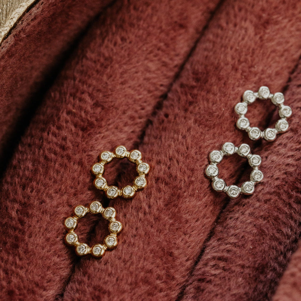 Pair of diamond stud earrings  in 14k yellow and white gold on a red fabric surface