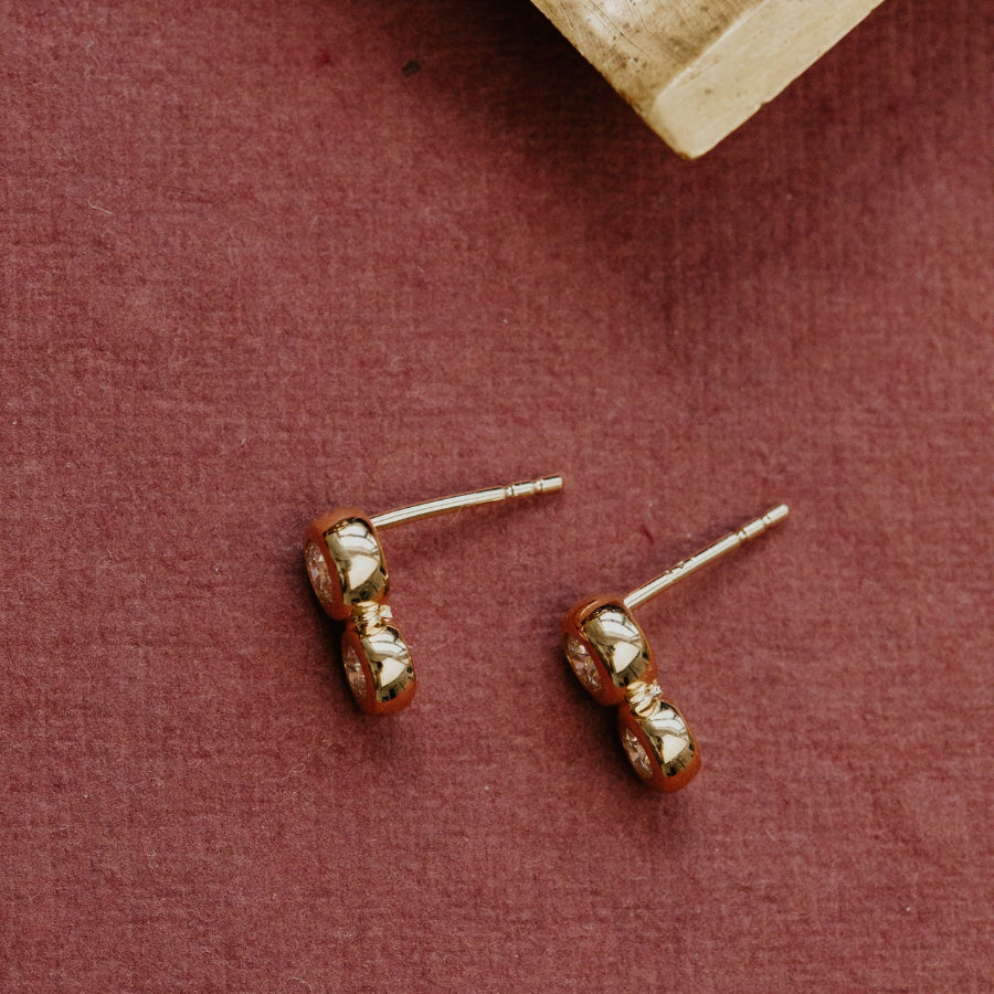 Gold stud earrings on a textured red surface