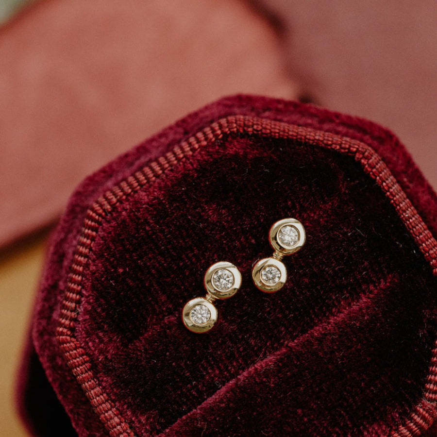 Gold diamond earrings on a red velvet surface