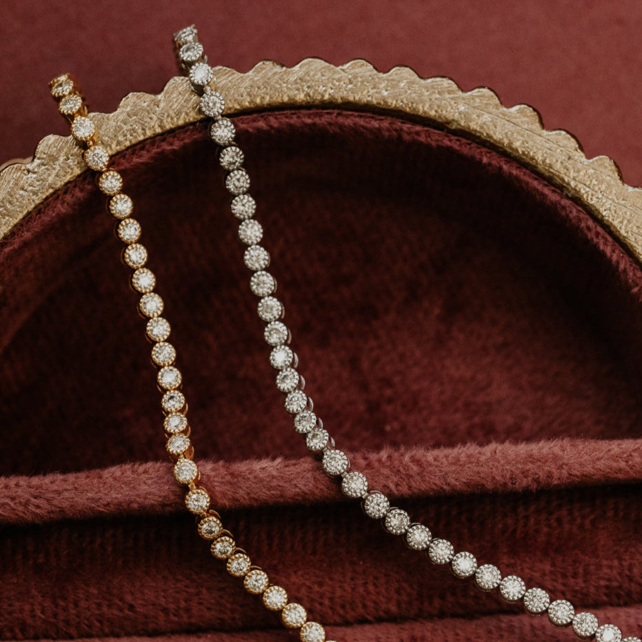 Diamond tennis bracelet draped over a red jewelry box with gold trim