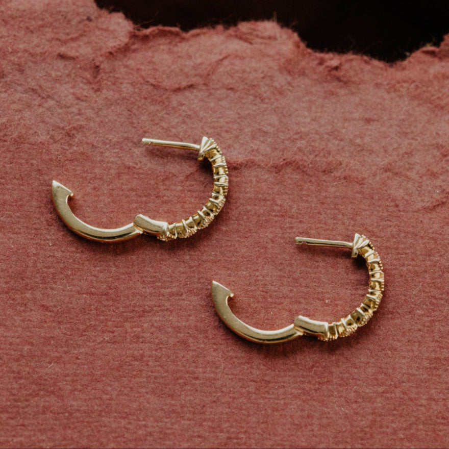 Gold hoop earrings on a textured pink surface