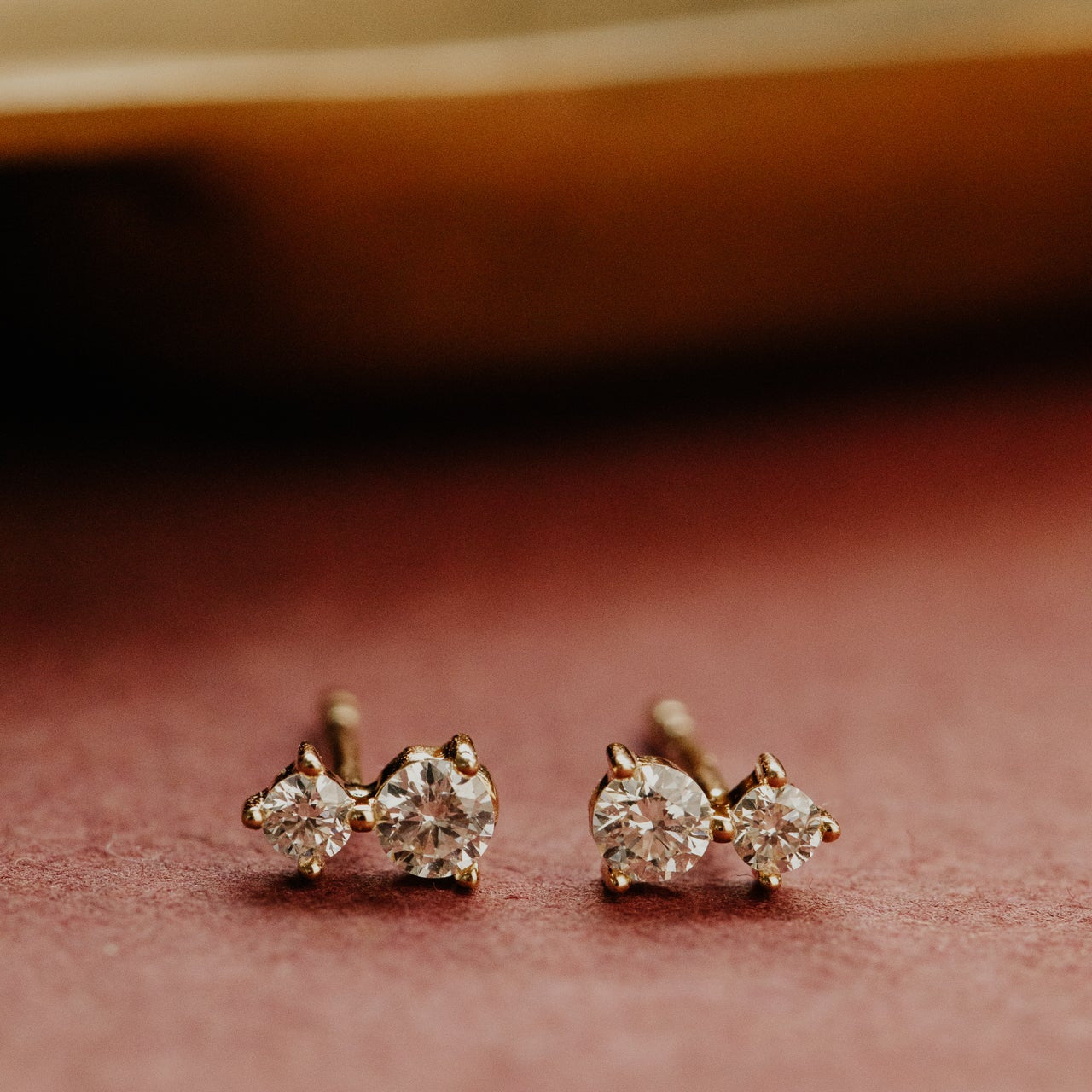 Pair of diamond stud earrings on a soft pink background