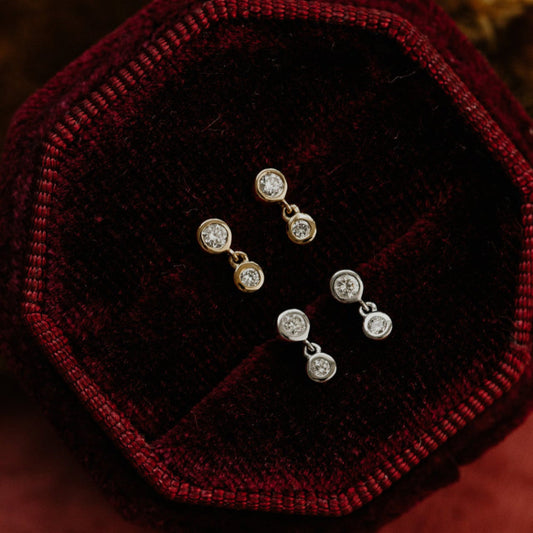 Pair of diamond stud earrings on a red velvet surface