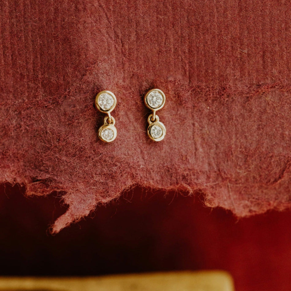 Pair of earrings on a textured red surface