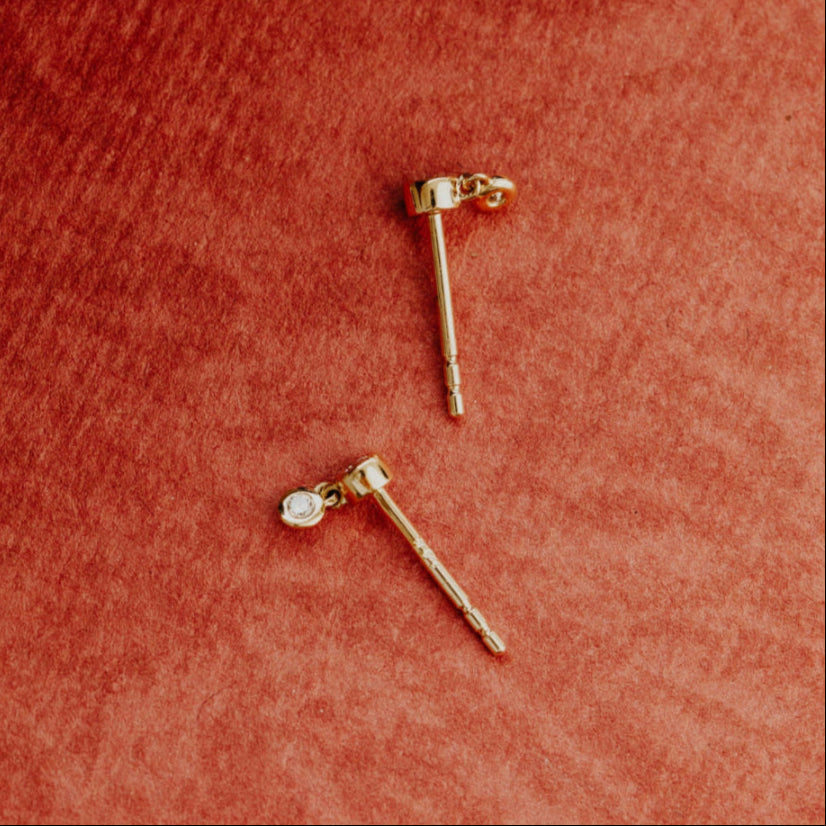 Gold earrings on a textured red surface