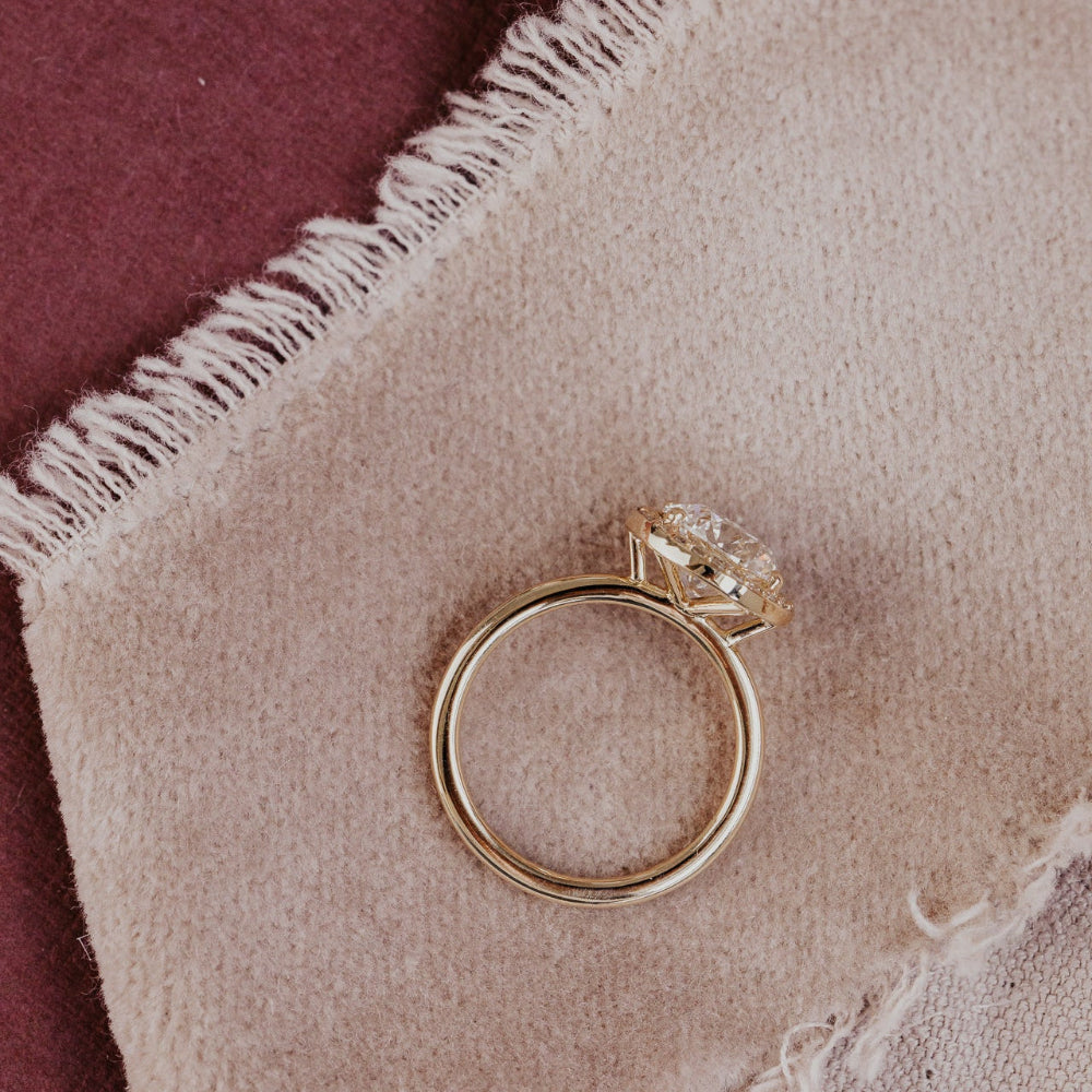 Gold ring with a round diamond on a textured fabric surface