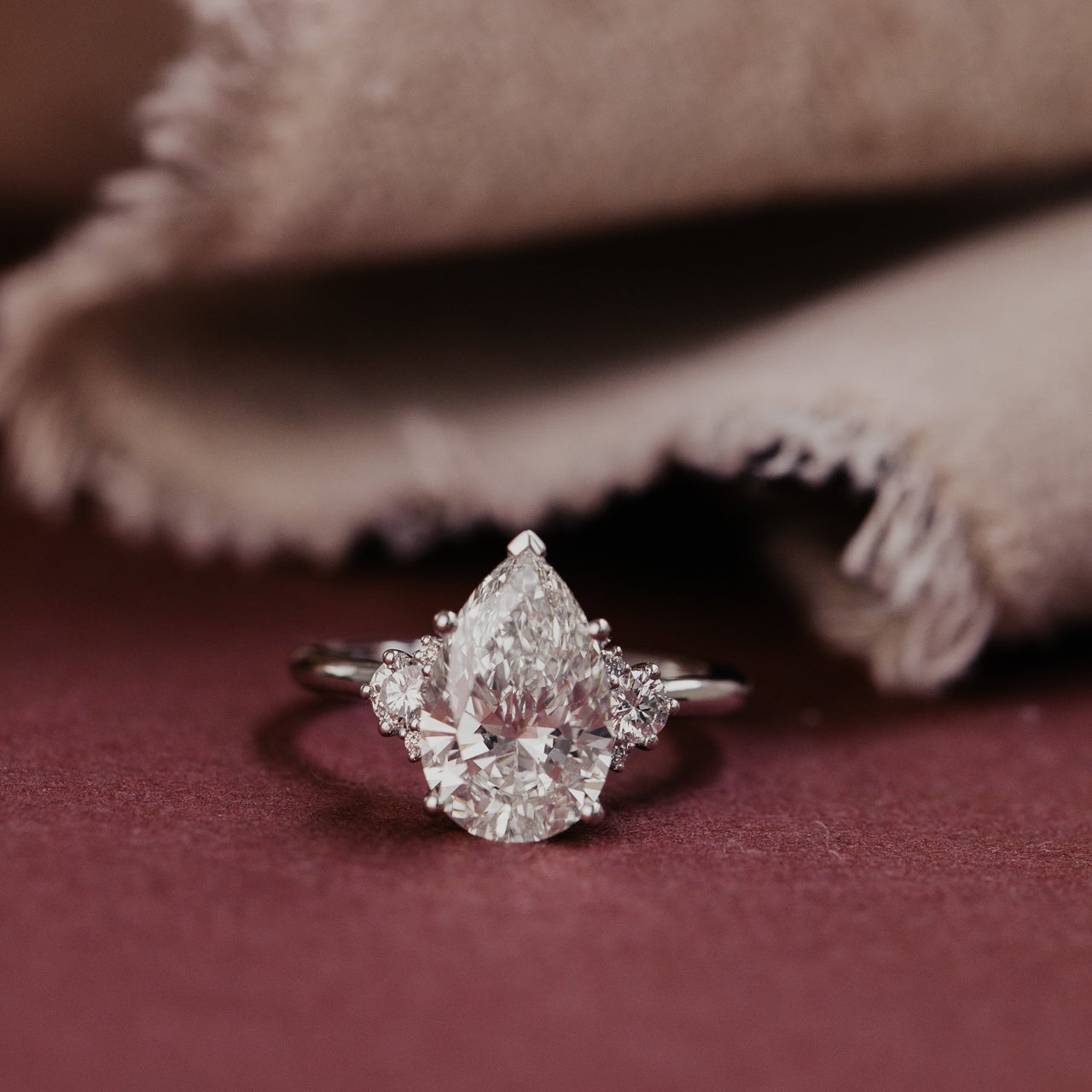Pear shaped lab grown diamond ring on a textured fabric background