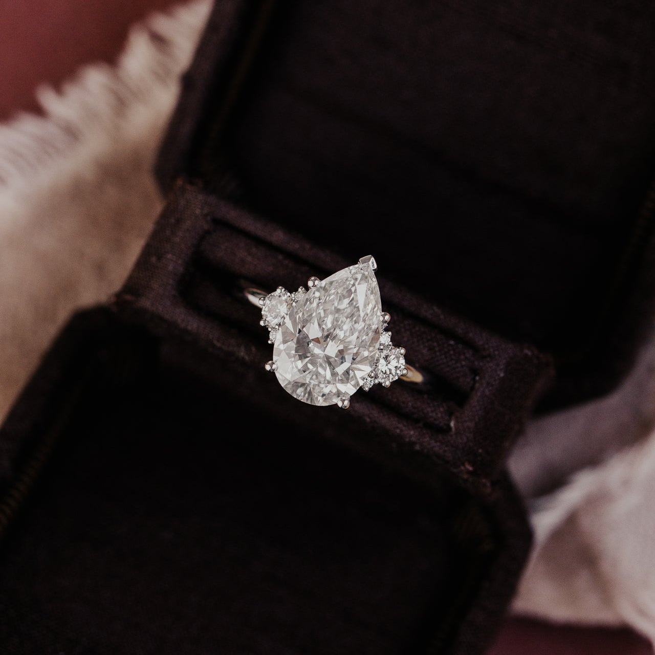 Pear shaped diamond ring on a dark fabric background
