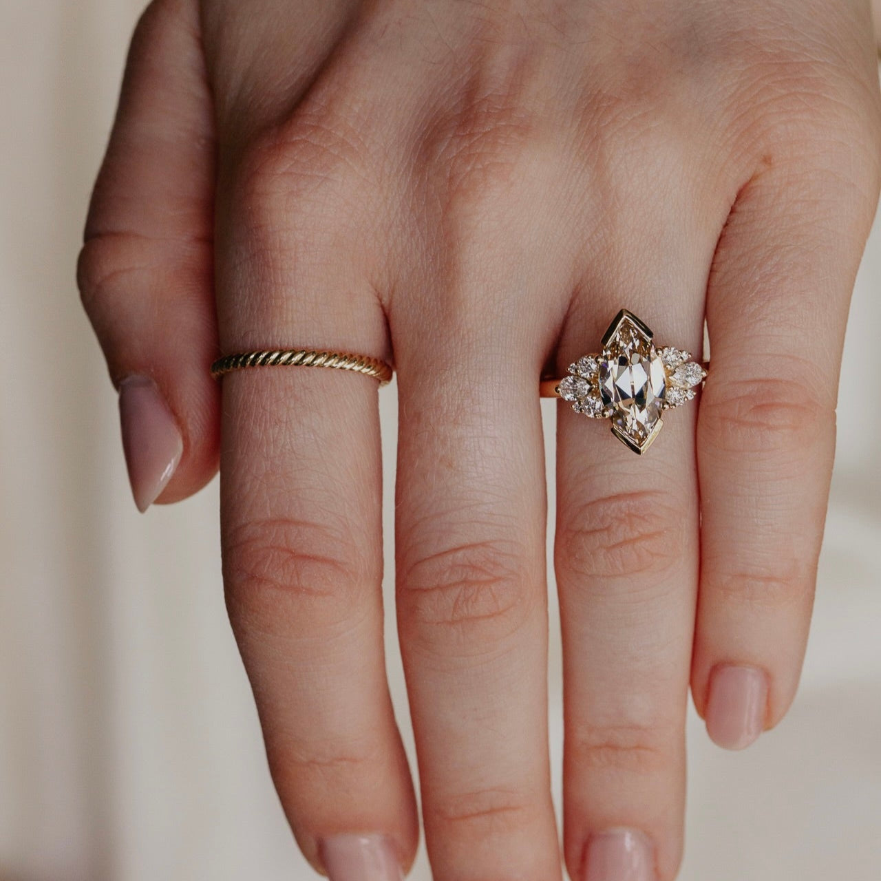 Hand wearing two rings with a plain background