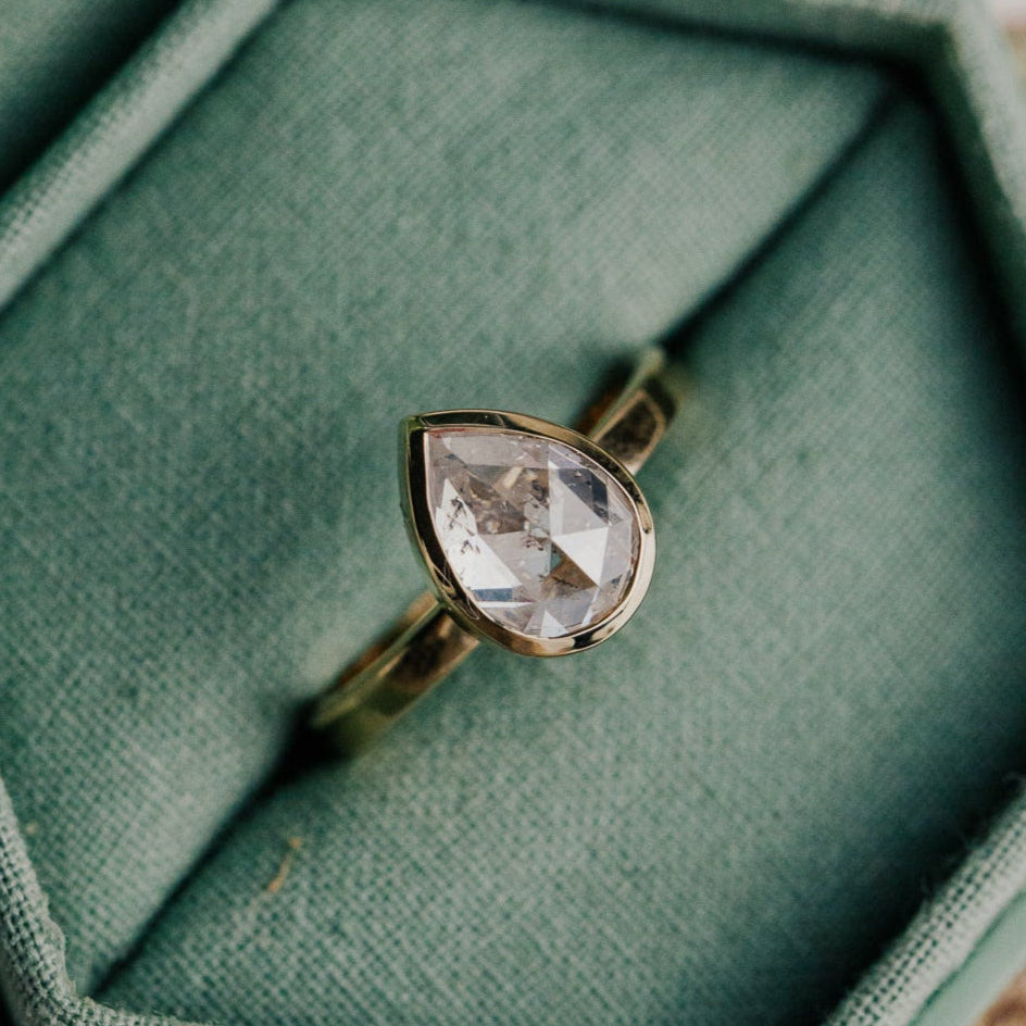 14k gold ring featuring a clear pear rustic rose cut diamond set in a bezel design.