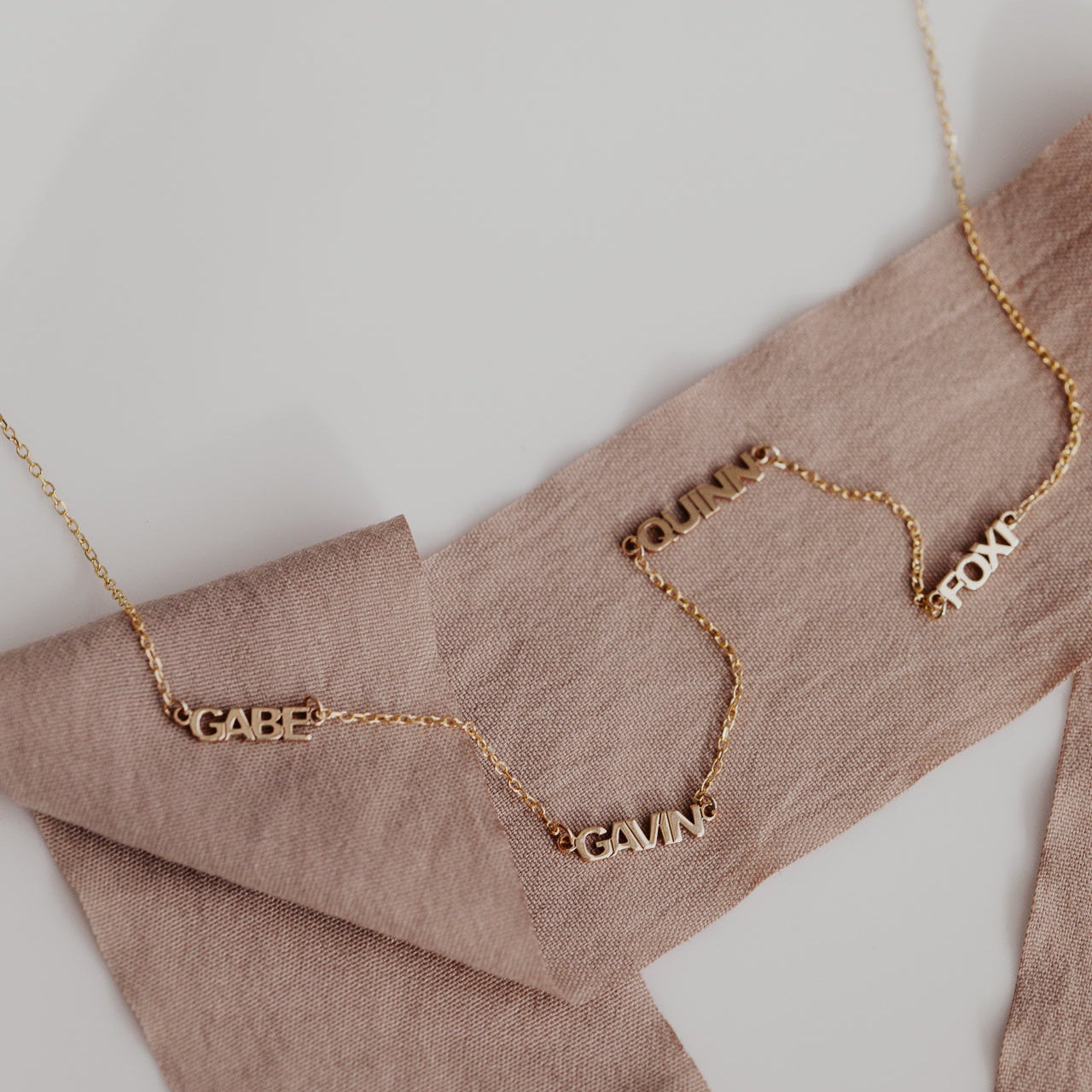 Personalized necklace with 4 custom names set on a 14k gold chain
