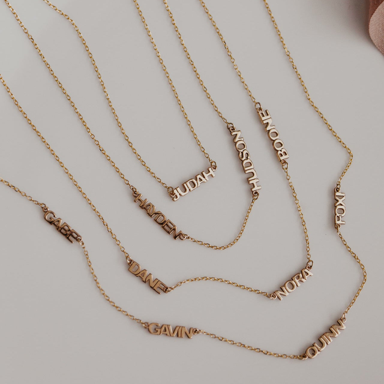 Four personalized necklaces with up to 4 custom names set on a 14k gold chain