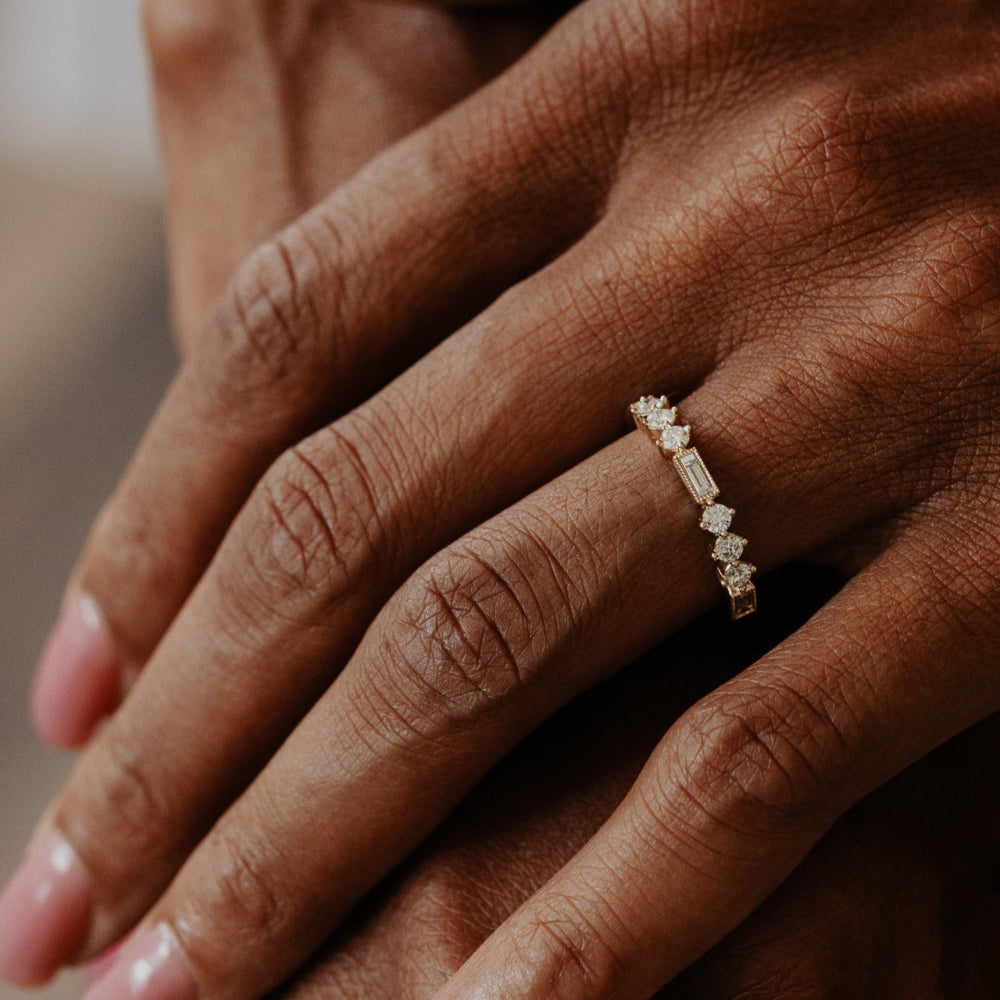 Close-up of a hand wearing a diamond band with a blurred background