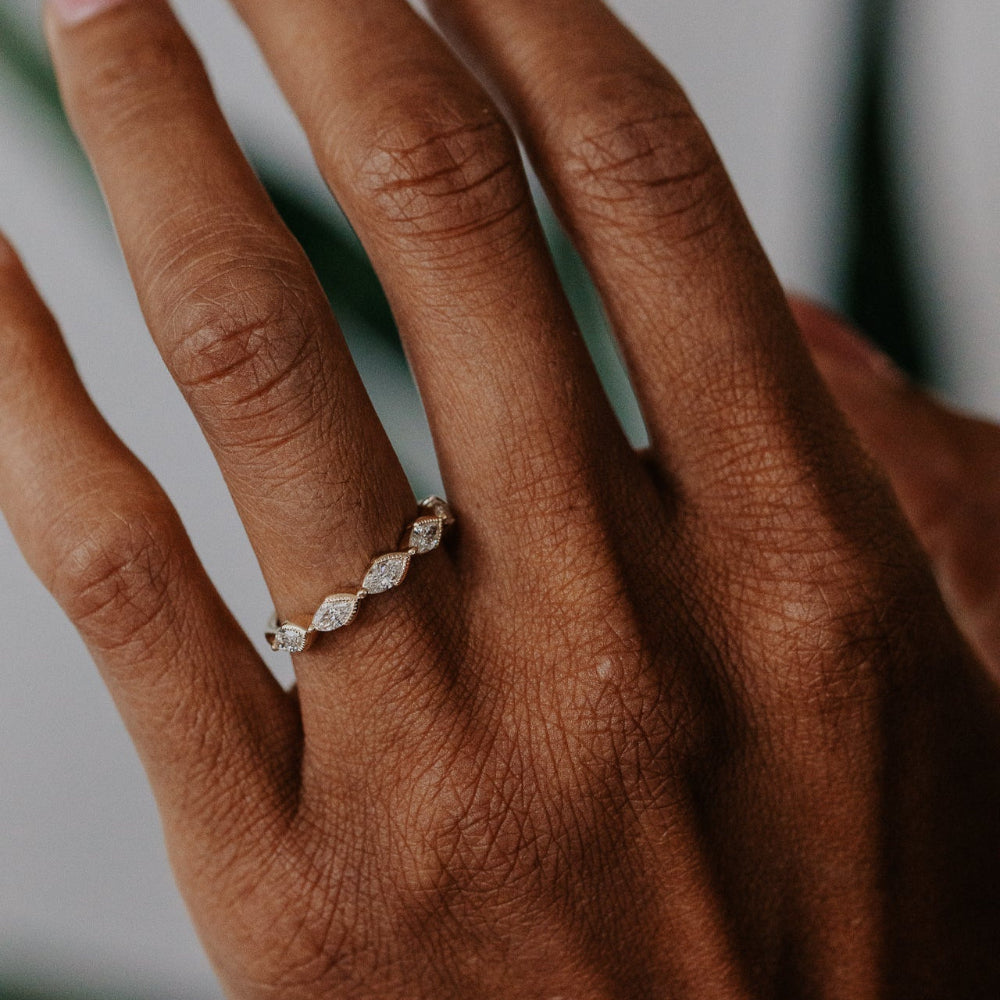 Hand wearing a marquise diamond band with a blurred background