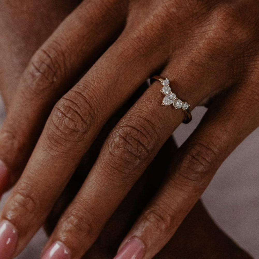 14k gold wedding band with round and oval diamonds, set in prongs in a starburst design.