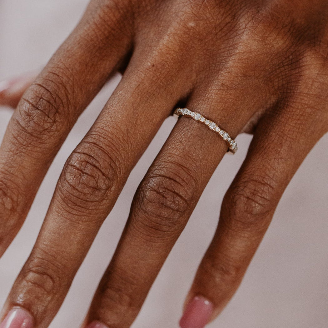 14k gold band  featuring ~.29 cttw pave round diamonds in a wave pattern 