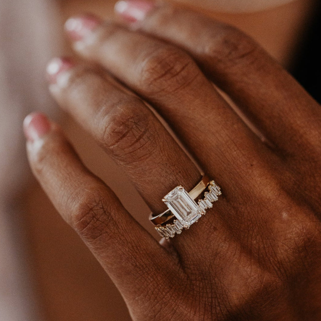 14k gold band featuring ~.48 cttw baguette diamonds set in a staggered design paired with Emerald Cut Diamond Solitaire ring