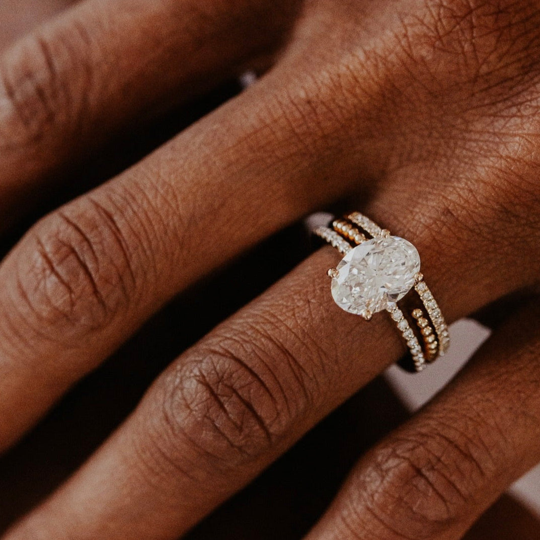 14k gold wedding band featuring a ~.10 cttw pave diamond band, with an open beaded texture band paired with a oval diamond solitaire ring.