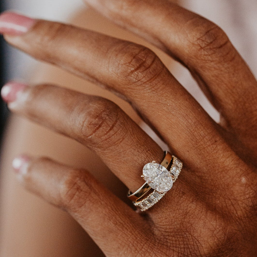 14k gold band featuring ~.49 cttw baguette and double round diamonds set in prongs in an alternating design paired with a oval diamond solitaire ring