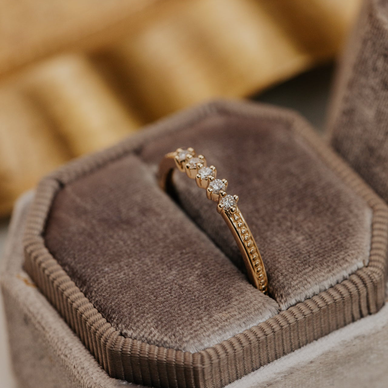 round diamonds set in prongs on a flat 14k gold wedding band with a milgrain texture