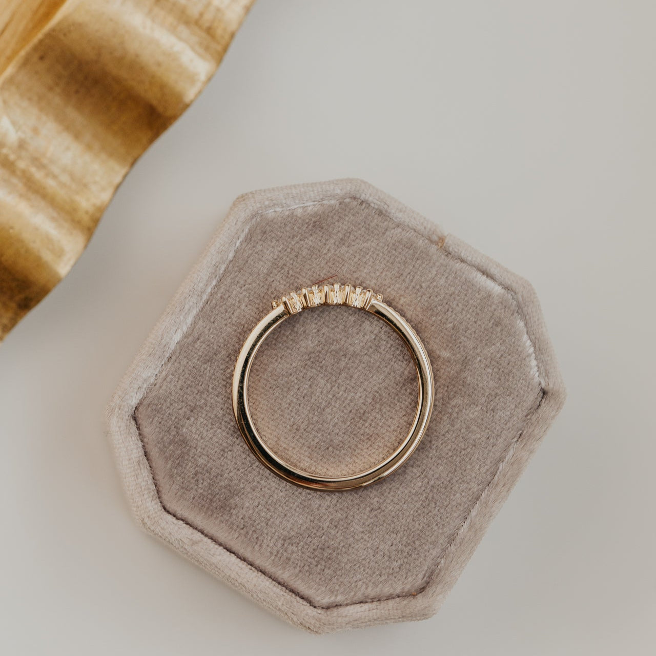 round diamonds set in prongs on a flat 14k gold wedding band with a milgrain texture