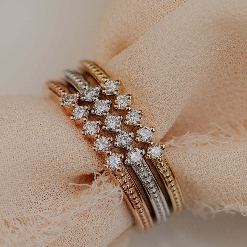 round diamonds set in prongs on a flat 14k gold wedding band with a milgrain texture