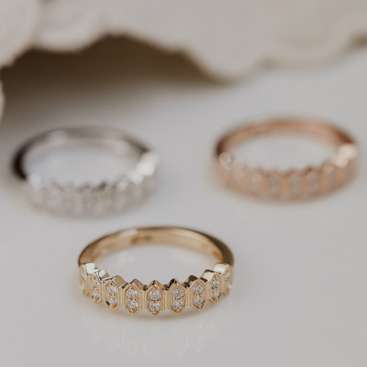 14k gold wedding band featuring round diamonds set in an elongated hexagon pattern.