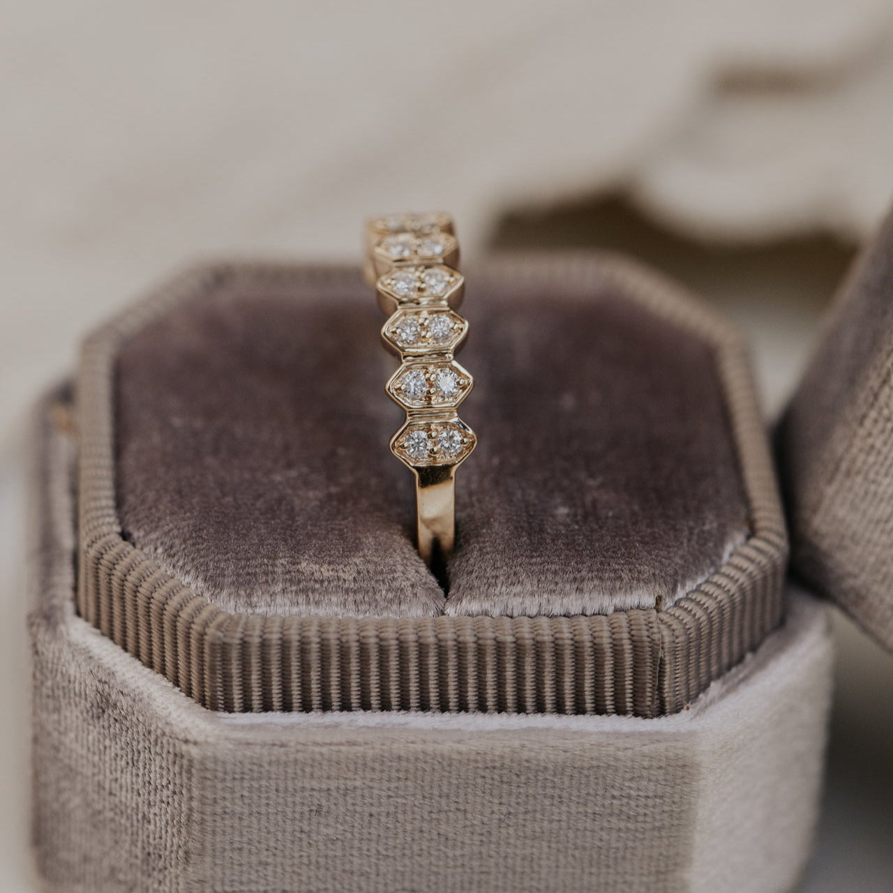 14k gold wedding band featuring round diamonds set in an elongated hexagon pattern.