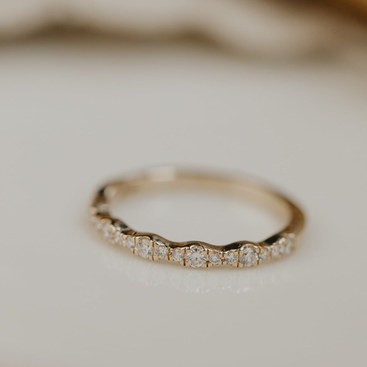 14k gold band  featuring ~.29 cttw pave round diamonds in a wave pattern 