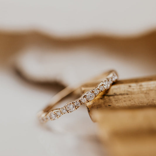 14k gold band  featuring ~.29 cttw pave round diamonds in a wave pattern 