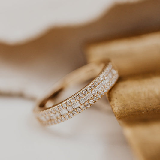 14k gold wedding band with alternating horizontal baguette and round diamonds set between two rows of round pave diamonds.