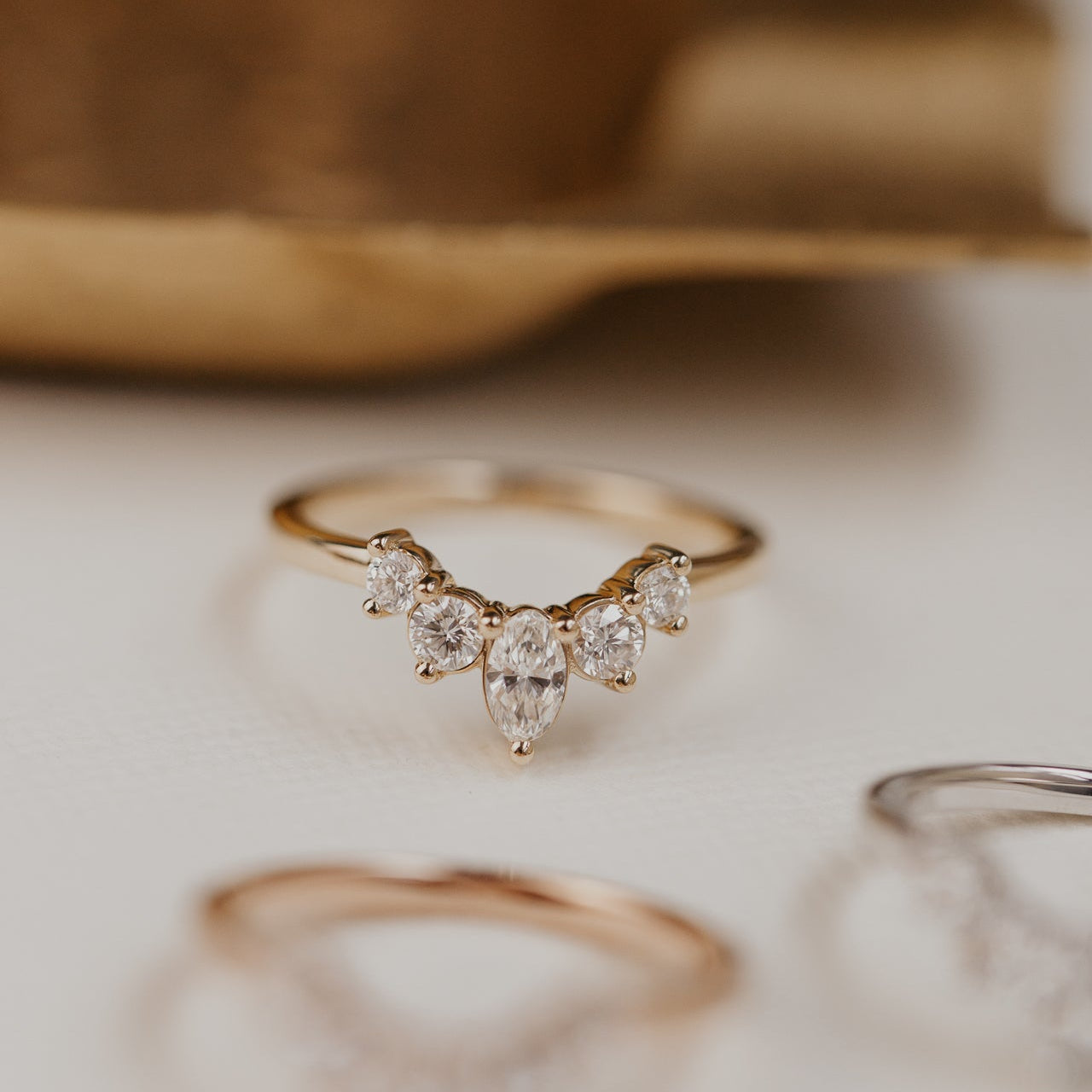 14k gold wedding band with round and oval diamonds, set in prongs in a starburst design.