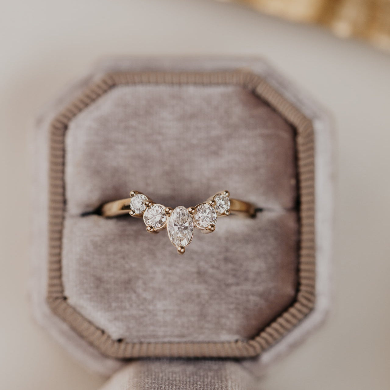 14k gold wedding band with round and oval diamonds, set in prongs in a starburst design.