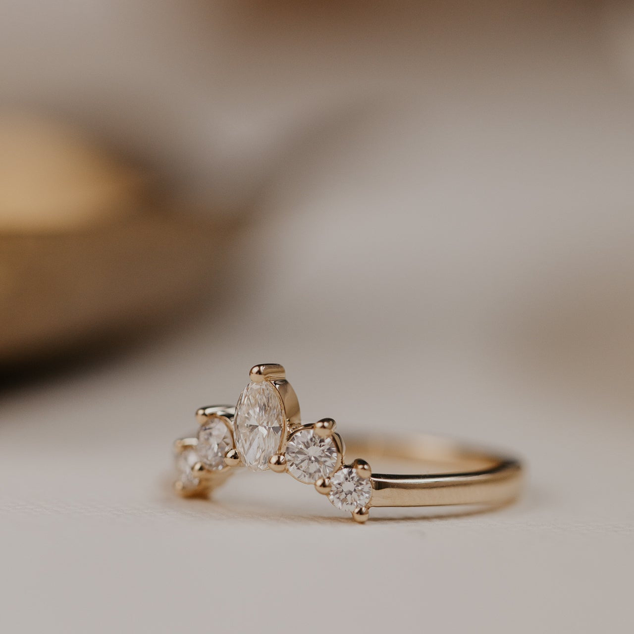 14k gold wedding band with round and oval diamonds, set in prongs in a starburst design.