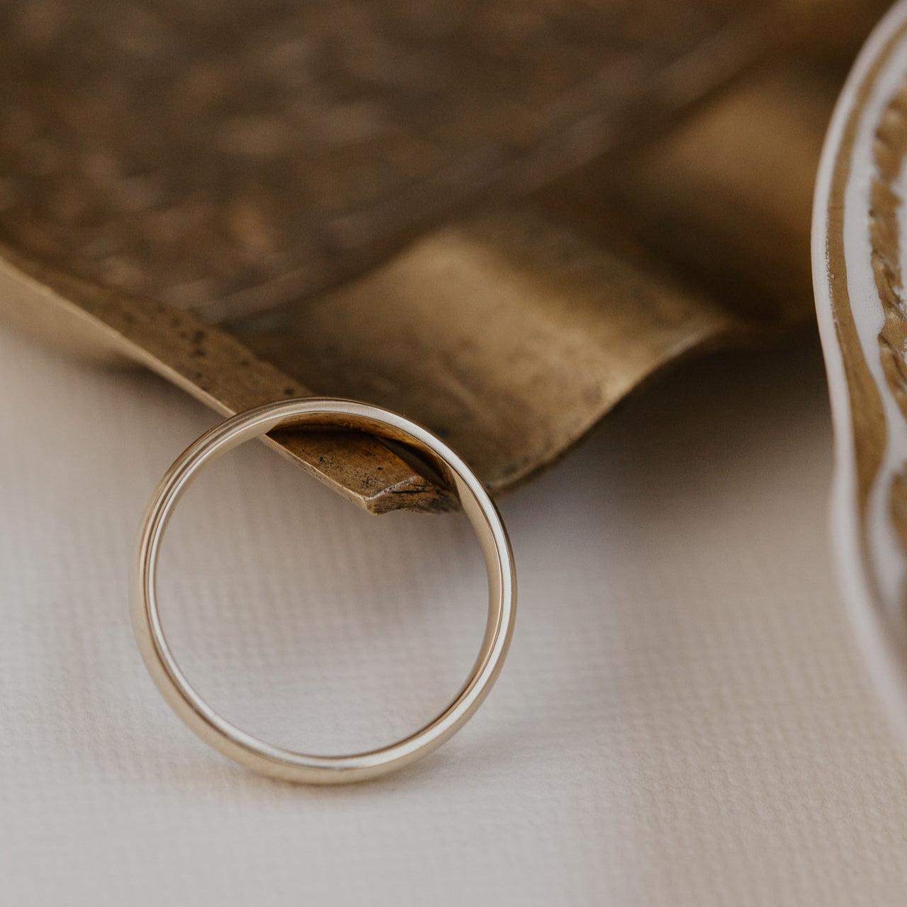 Gold ring on a textured surface with a brown paper bag in the background