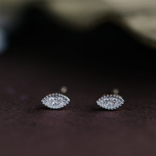 Pair of gold marquise-shaped diamond earrings on a dark surface.