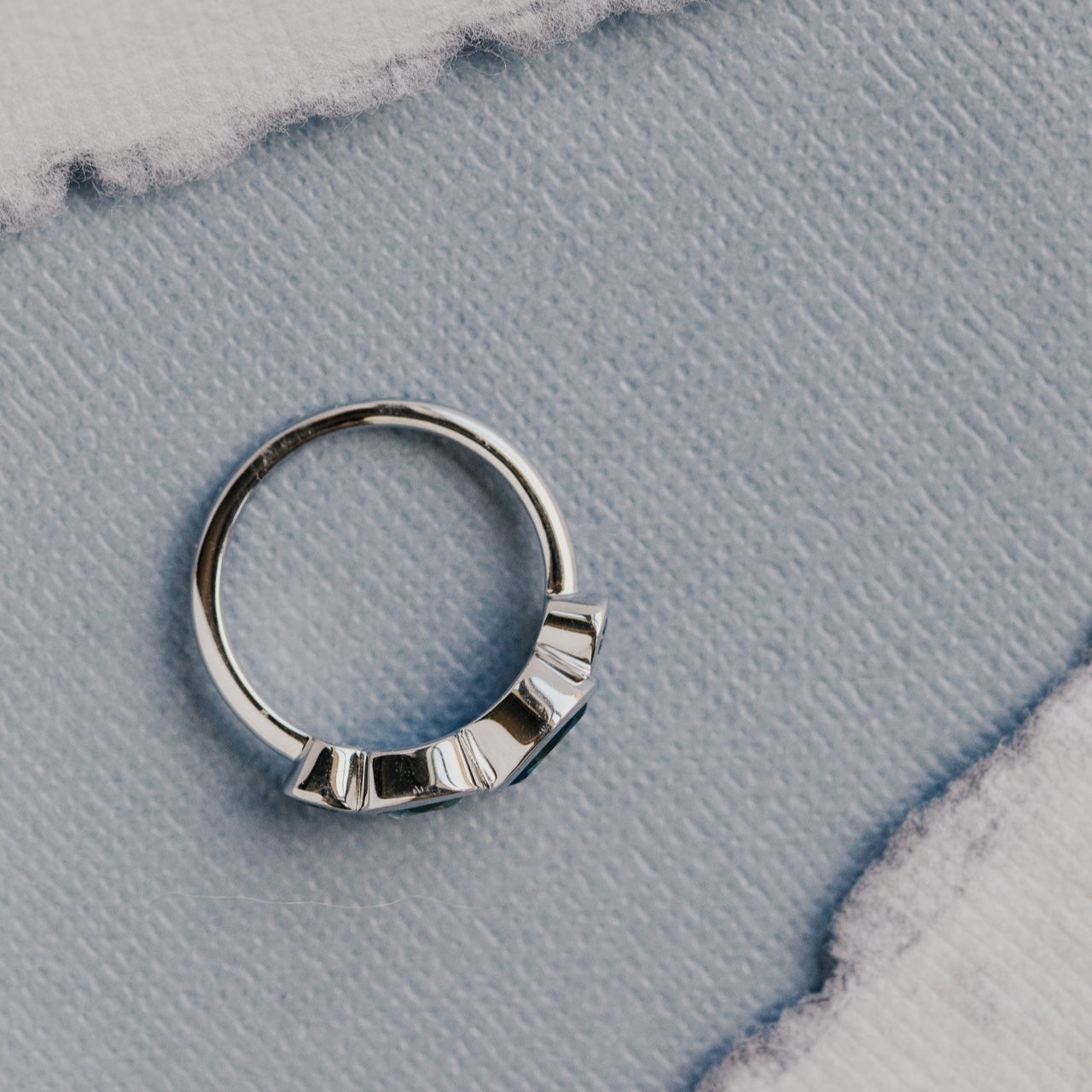 white gold ring with geometric design on a textured blue surface