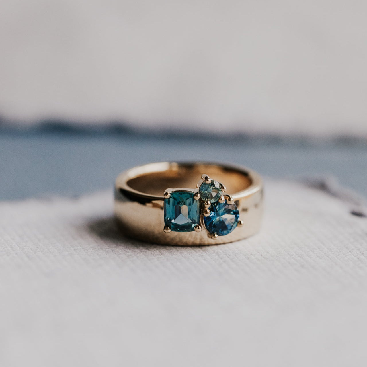 Gold ring with blue sapphires on a textured surface