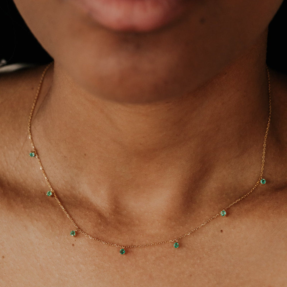 Necklace with green emerald gemstones worn by a person.