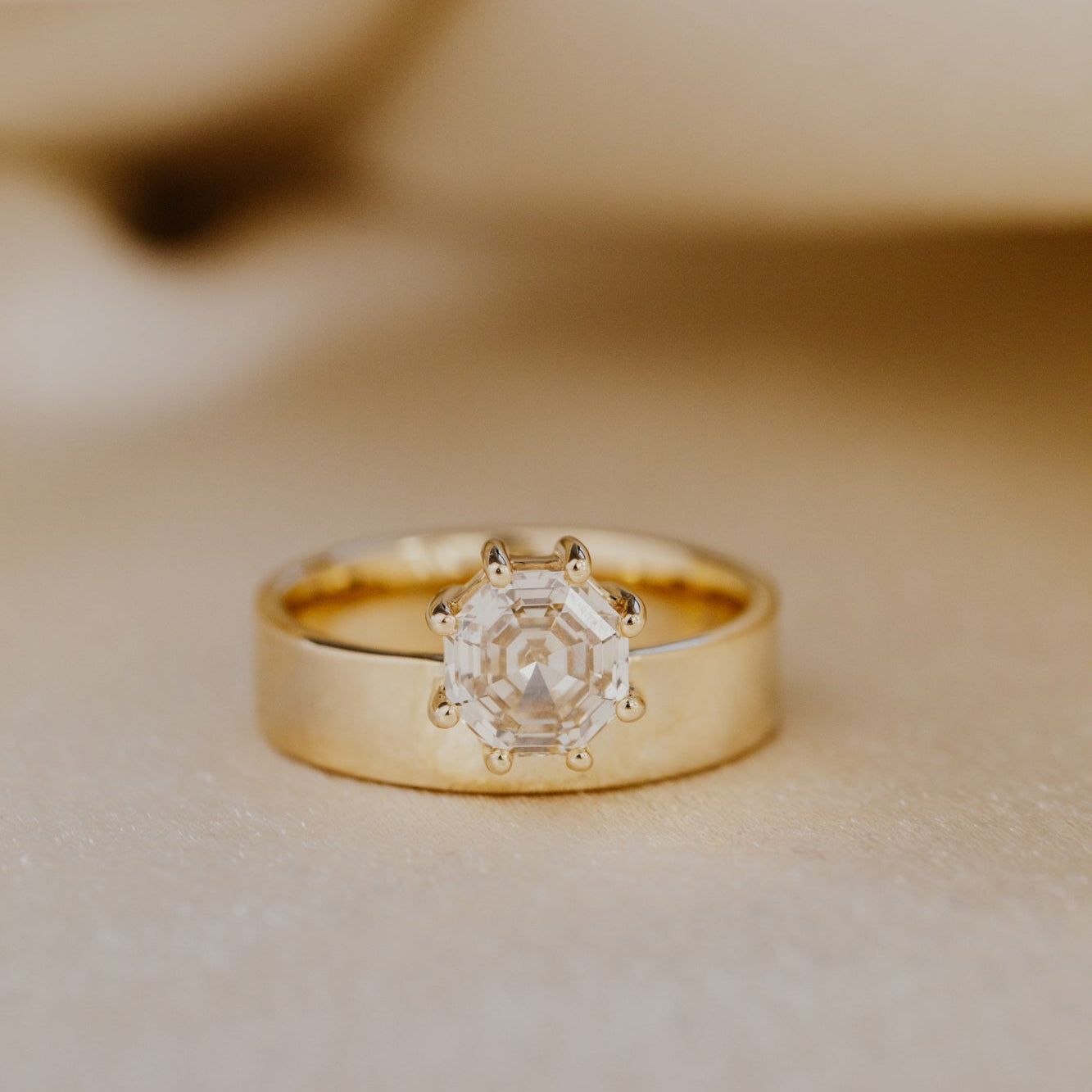 Gold ring with a octagon champagne diamond on a beige background.