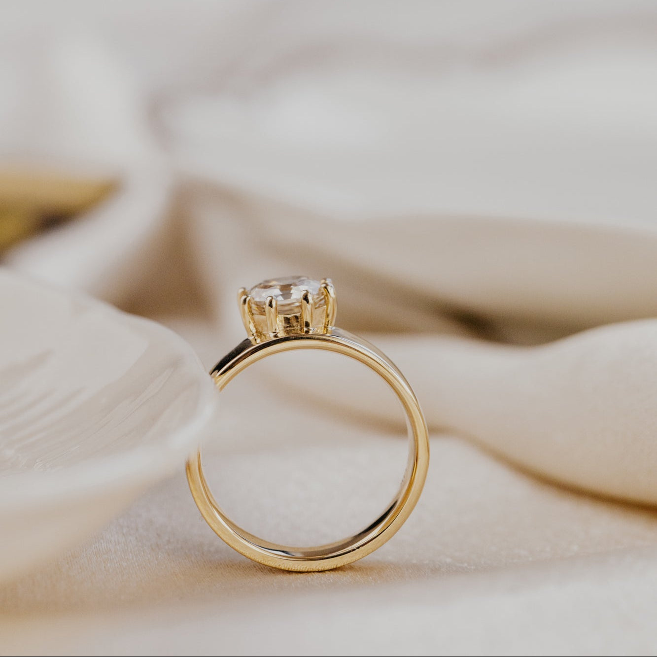 Gold ring with a champagne diamond on a soft beige background.