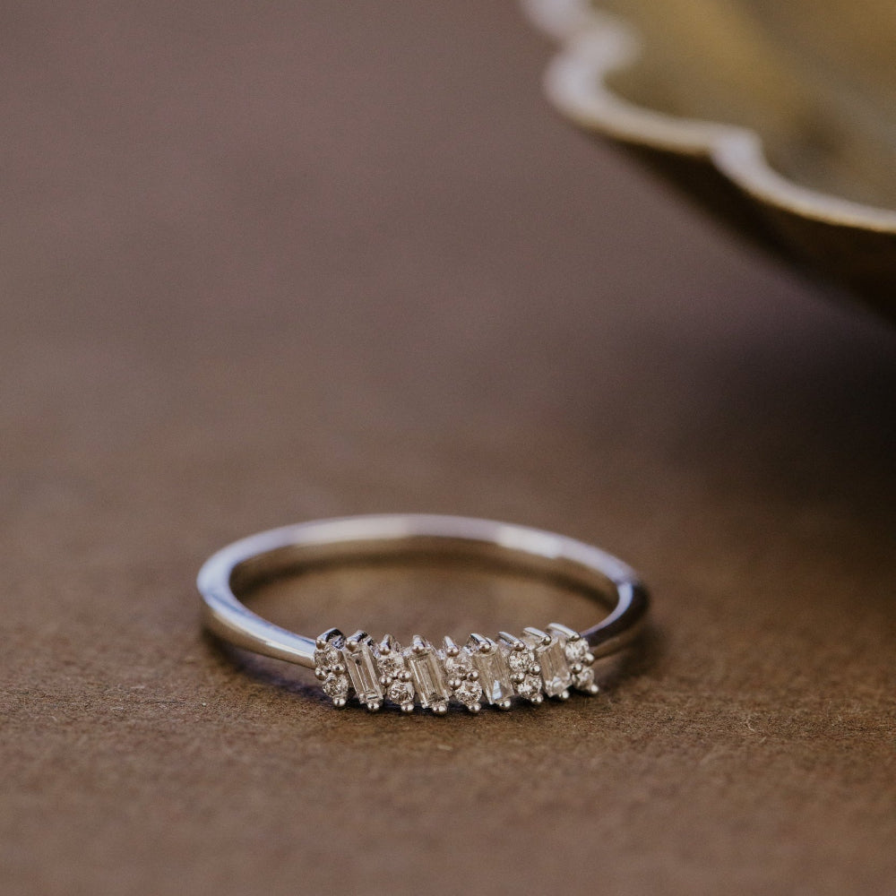 White gold wedding band with diamond accents on a brown surface.