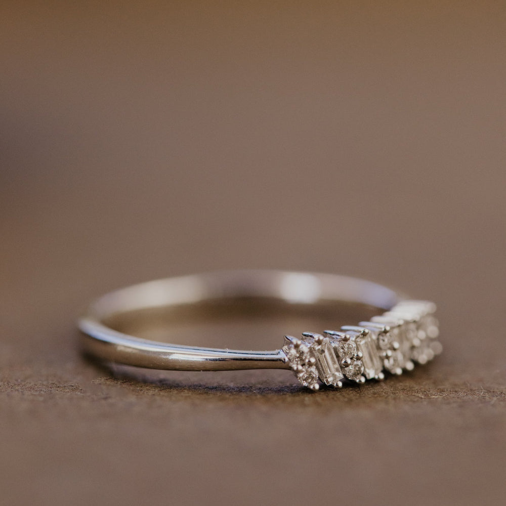 White gold wedding band with a textured design on a brown background.