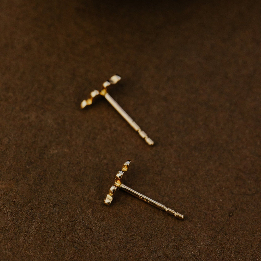 Two gold earrings on a brown surface.