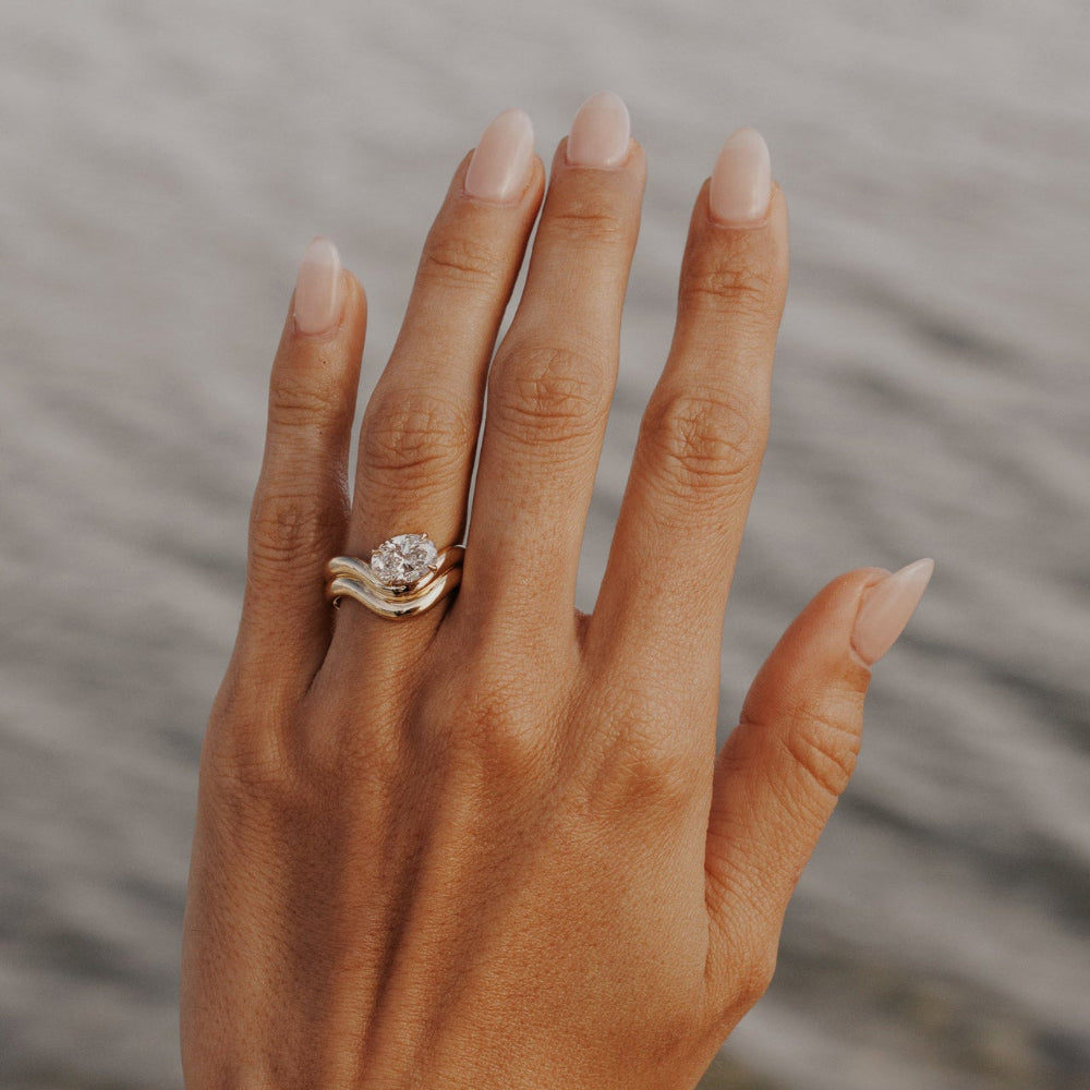 The Capri Oval Ring in 14k yellow gold featuring a lab-grown oval diamond prong set on a double wavy band, worn on the ring finger.