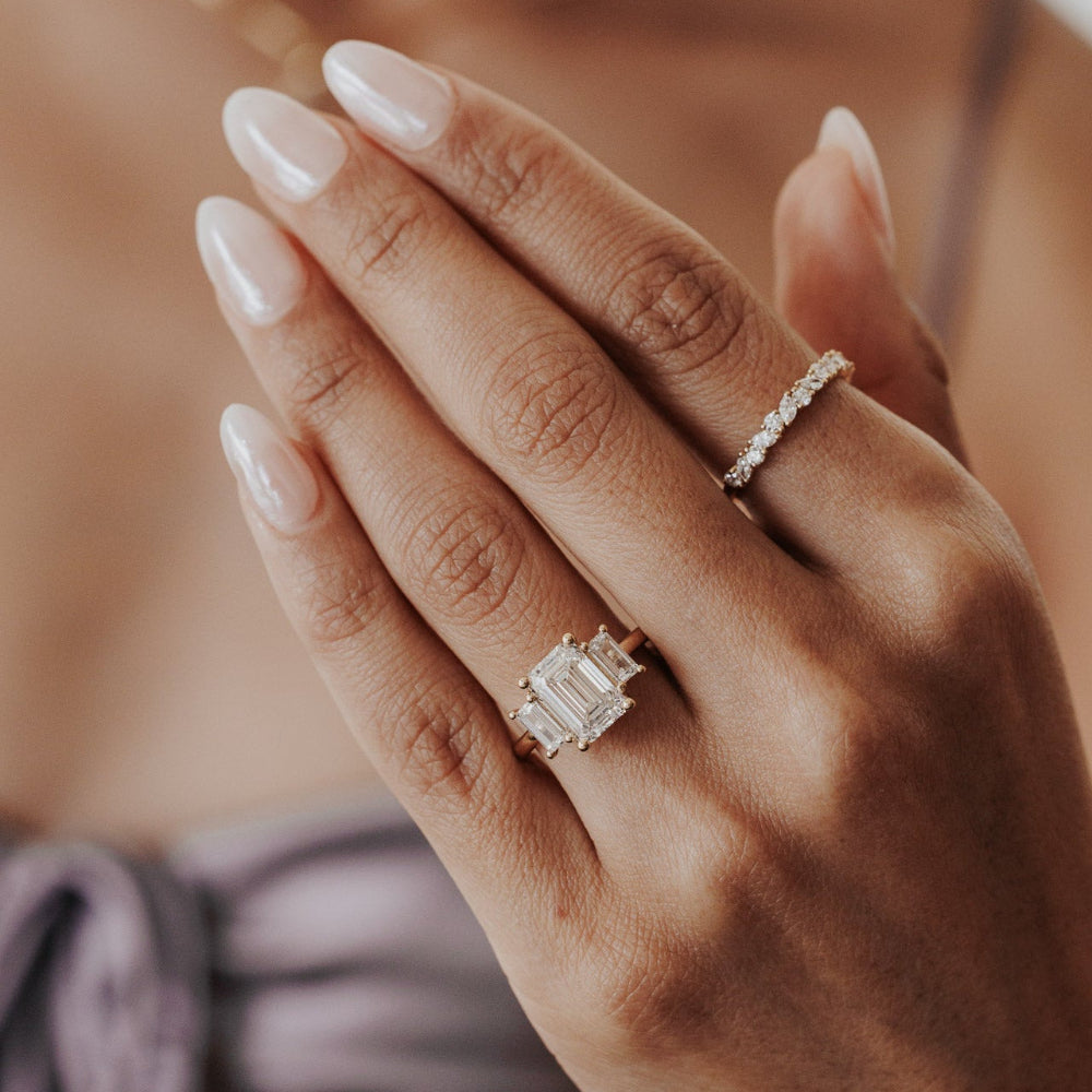 The Hannah Emerald Cut Ring in 14k yellow gold worn on the ring finger, styled with a diamond eternity band on the middle finger.
