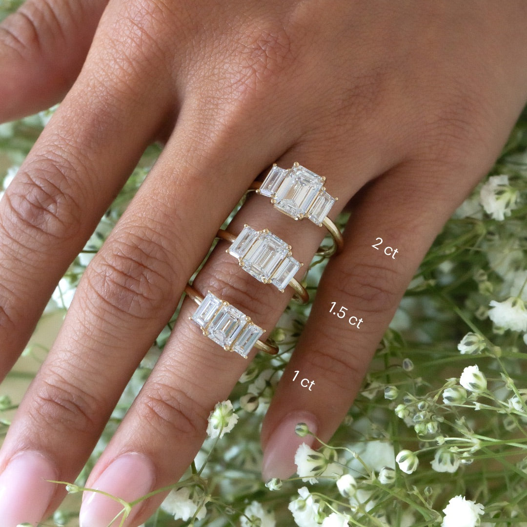 The Hannah Emerald Cut Ring in 14k yellow gold shown in three center stone size options worn on the hand: 2 ct, 1.5 ct, and 1 ct.