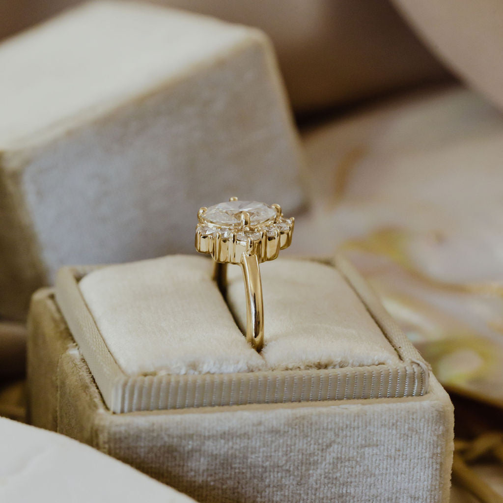 The Horizon Oval Ring in 14k yellow gold featuring a lab-grown oval diamond center stone with a round tapered diamond half halo, displayed upright on a velvet ring box.